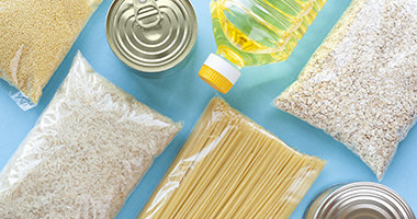 Person carrying a box of canned and dry foods